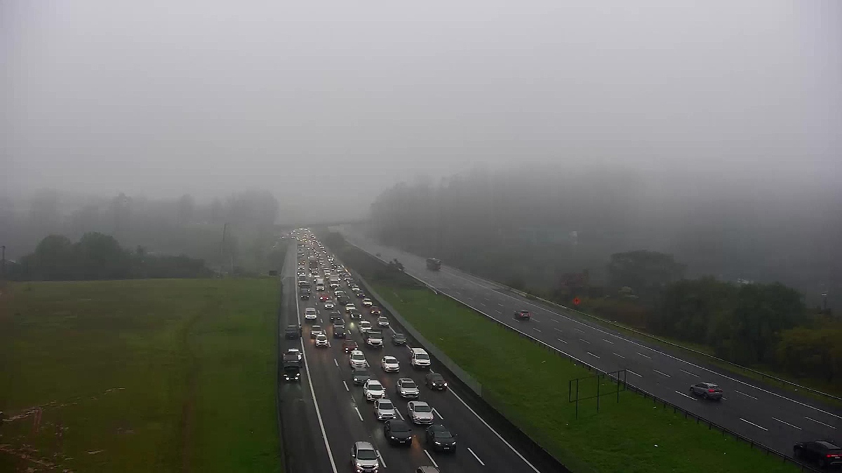 Rodovia registra trânsito intenso sob forte neblina em trecho de serra, com baixa visibilidade e fluxo lento de veículos