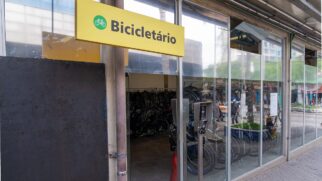 Fachada de vidro de um bicicletário público em uma calçada de blocos de concreto