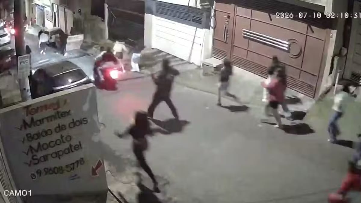 Captura de tela em ângulo superior de uma câmera de segurança noturna identificada como "CAM01" no canto inferior esquerdo. Em uma rua residencial iluminada por postes, várias pessoas correm em direções opostas em sinal de desespero e correria. No centro, destaca-se um homem de costas correndo, e ao fundo uma motocicleta em movimento com a lanterna traseira acesa