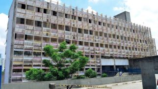Fotografia diurna e frontal do prédio do Hospital Municipal de Ermelino Matarazzo, na Zona Leste de São Paulo. A fachada principal do edifício de vários andares é coberta por uma estrutura quadriculada de concreto estilo quebra-sol (brise-soleil)