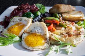 Mesa de brunch composta por ovos, pães e folhas