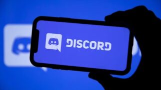 Mão segurando um celular mostrando a logo do Discord