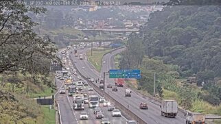 Imagem de câmera de monitoramento viário no km 20 da Rodovia Anhanguera (SP-330), sentido São Paulo (Sul). À esquerda, as faixas de rolamento exibem intenso fluxo de veículos com fila de carros, ônibus e caminhões em trânsito lento. À direita, as faixas de acesso ao Rodoanel Mário Covas (Saída 22) apresentam tráfego normal. Ao centro, destaca-se uma grande placa azul de sinalização rodoviária sobre a pista e, no topo superior esquerdo, um banner com dados técnicos da concessionária CCR AutoBān.