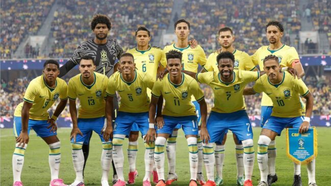 Fotografia oficial dos onze jogadores titulares da Seleção Brasileira de Futebol alinhados no relvado antes de uma partida amigável, a vestir a camisola amarela tradicional, calções azuis e peúgas brancas, com o guarda-redes e o capitão a segurar o flâmula do jogo perante bancadas compostas por adeptos