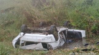 Fotografia de um automóvel ligeiro branco capotado virado ao contrário sobre a vegetação na berma da rodovia SP-055, no quilómetro 216 sentido oeste