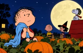 Linus com seu cobertor azul em um campo de abóboras durante o Halloween, acompanhado por Charlie Brown, Lucy e Snoopy sob a lua cheia.