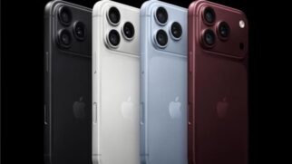 Fotografia em plano três quartos traseiro de quatro smartphones Apple iPhone perfilados lado a lado, exibindo as opções de cores preto, prateado, azul-claro e vinho. Os aparelhos destacam o módulo saliente de câmara tripla no canto superior esquerdo e o logótipo da maçã no centro do painel posterior