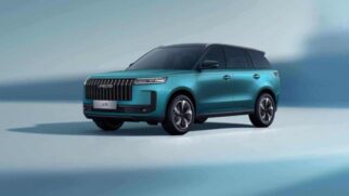 Fotografia de estúdio em ângulo três quartos dianteiro de um SUV Jaecoo 5 na cor azul turquesa metálico com teto preto. O modelo exibe grade frontal com filetes verticais, logotipo "JAECOO" na parte superior, faróis afilados e rodas de liga leve em estúdio com fundo azul suave