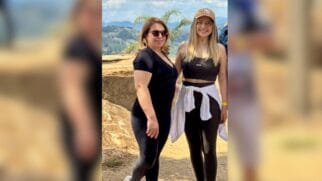 Fotografia de duas mulheres em vestuário desportivo num miradouro ao ar livre com paisagem montanhosa ao fundo, uma delas com t-shirt preta e óculos de sol, e a outra com top desportivo preto, boné bege e uma camisola branca atada à cintura
