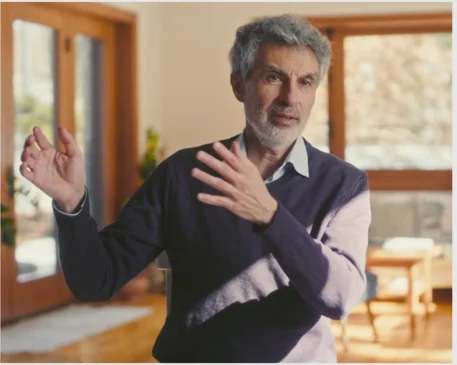 Yoshua Bengio gesticula durante entrevista sobre inteligência artificial em ambiente iluminado por luz natural.