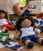 Uniformes antigos voltaram às mãos de crianças como bonecas e bonecos de pano feitos por costureiras da comunidade em uma nova entrega solidária