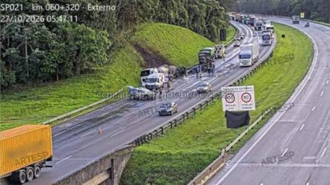 Imagem de câmara de monitorização viária mostrando acidente grave no km 60 da Rodovia Rodoanel Mario Covas (SP-021), com múltiplos veículos e camiões imobilizados nas faixas de rodagem, gerando retenção no tráfego e presença de equipas de resgate