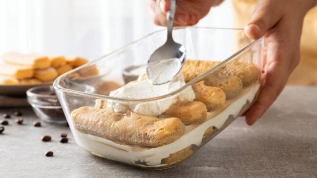 Umedecer rapidamente os biscoitos no leite ajuda a manter as camadas inteiras durante a montagem e evita que se desfaçam na travessa.