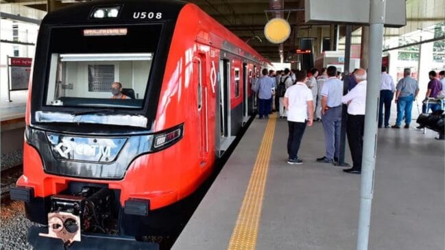 Comboio metropolitano da CPTM nas cores vermelha e preta, com a identificação U508, parado na plataforma de uma estação coberta, enquanto passageiros e técnicos acompanham a operação no cais