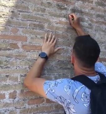 Homem de nacionalidade desconhecida vandaliza muro do Coliseu, em Roma