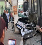 Veículo ficou esmagado entre o poste e o ônibus