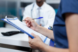 Enfermeira segura uma prancheta e anota informações ao lado de médico