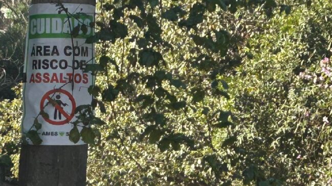 Placa afixada em rua de Pinheiros, em SP, alerta para alta de assaltos na região