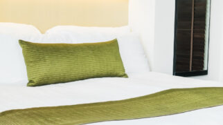 Para que serve a faixa de tecido sobre a cama dos hotéis?