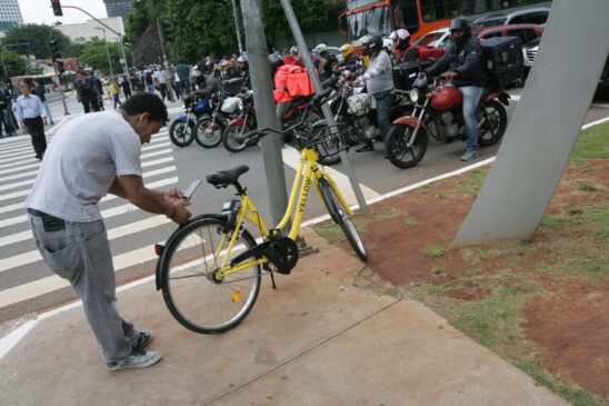 Usuário destrava bicicleta da Yellow com o seu celular na avenida Brigadeiro Faria Lima na esquina com a avenida Rebouças