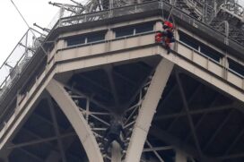 Um homem (abaixo na imagem) tentou escalar a torre em Paris; membros da polícia e dos bombeiros foram enviados ao local