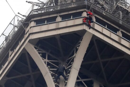 Um homem (abaixo na imagem) tentou escalar a torre em Paris; membros da polícia e dos bombeiros foram enviados ao local
