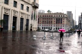 Pedestres se protegem da chuva na região da Praça Ramos de Azevedo, no centro de São Paulo, na manhã desta segunda