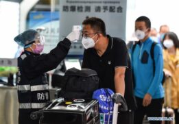 Pessoas usam máscaras e passam por verificação de temperatura em aeroporto na China