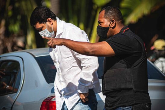 Marcos Duarte da Cruz, acusado de ser administrador oculto de instituto, sendo conduzido por agente do Ministério Público do Rio