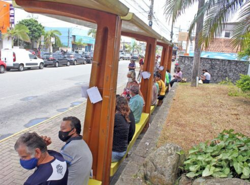 Diversas pessoas aguardam nos pontos de ônibus na avenida Condessa de Vimieiros, no Centro de Itanhaém